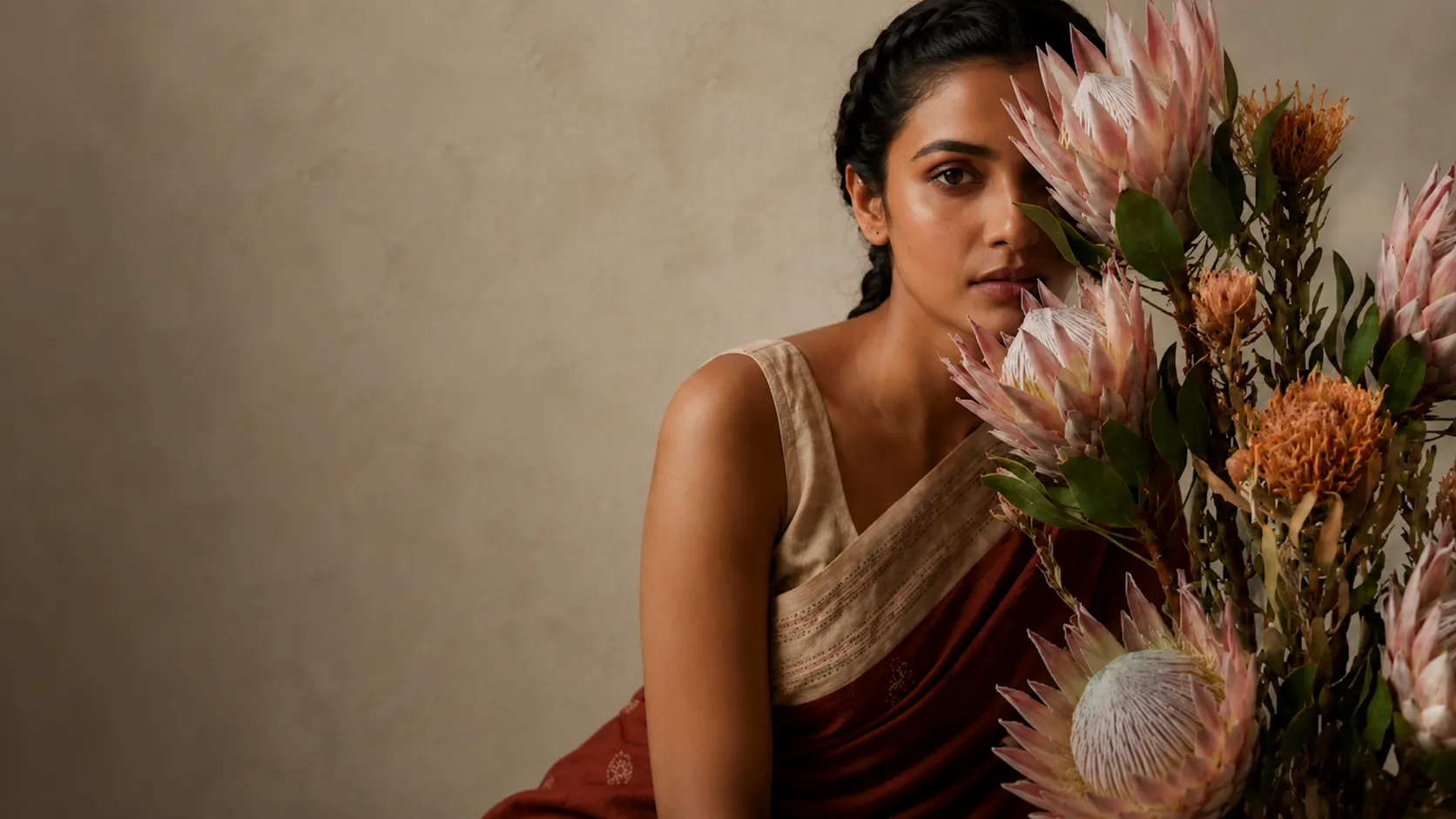 Woman in a terracotta handloom saree with protea blooms — Naholi, heritage worn softly